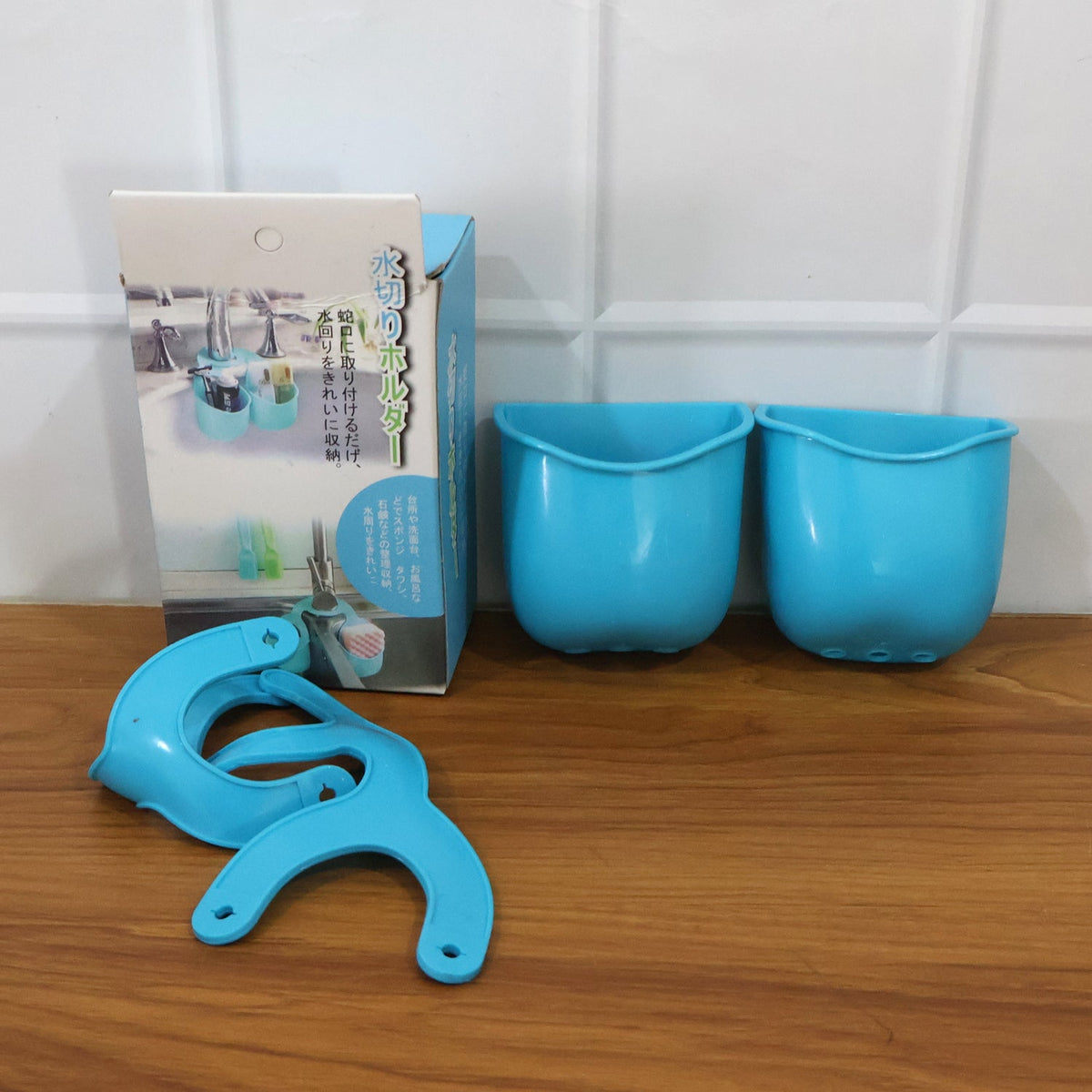 Blue plastic sink caddy components and its packaging box on a wooden surface.