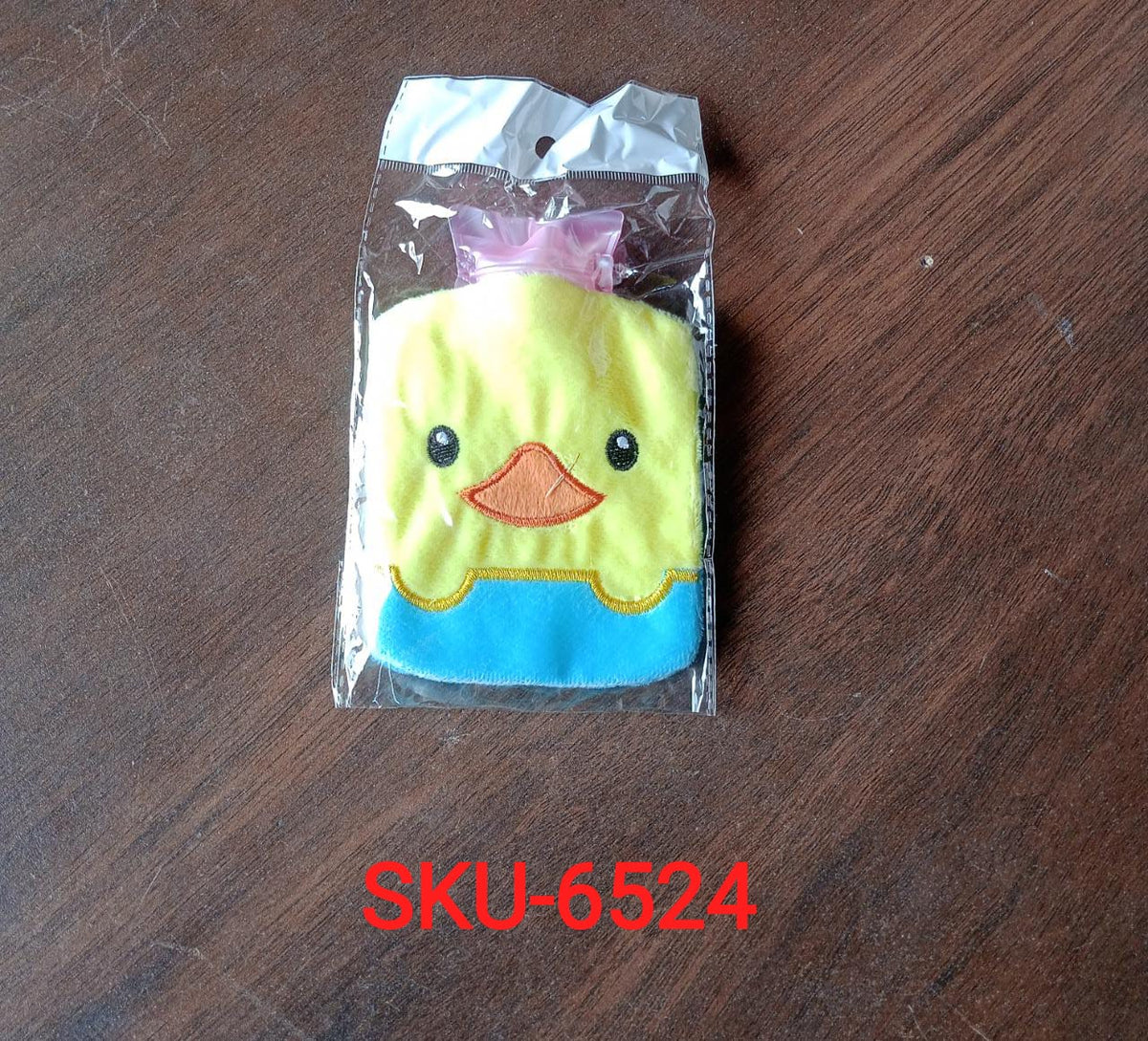 The yellow duck hot water bag is sealed in clear plastic packaging on a wooden surface.