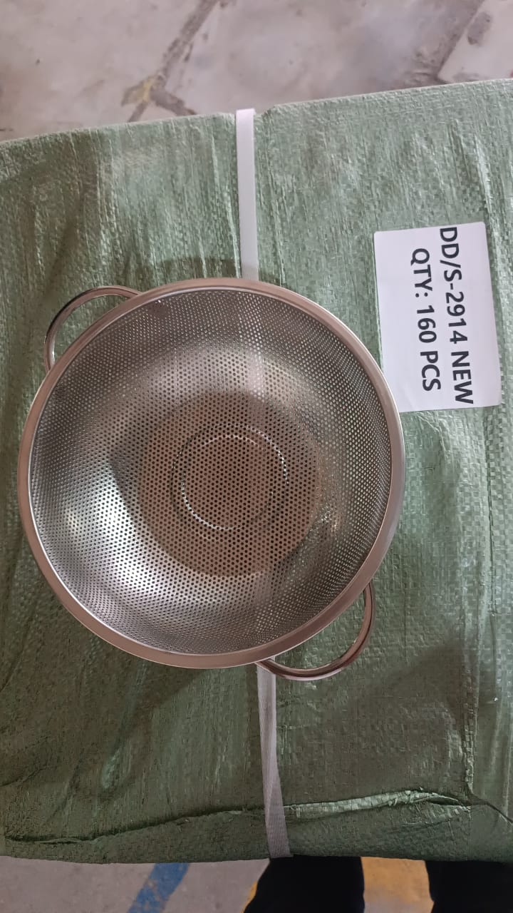 A stainless steel strainer bowl with handles resting on a green woven bag with a label indicating quantity.