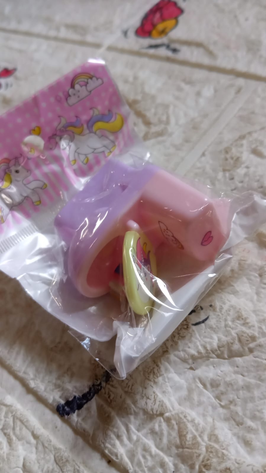 A pastel pink and purple toilet-shaped pencil sharpener with a unicorn eraser is sealed in clear plastic packaging with a