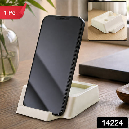 A black smartphone stands vertically in a cream plastic holder on a wooden table, with a red "1 Pc" tag and product number.