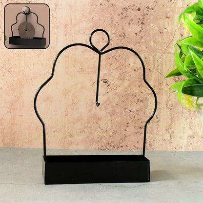 A black metal mosquito coil holder with a rectangular base is displayed against a textured beige wall. – view 4