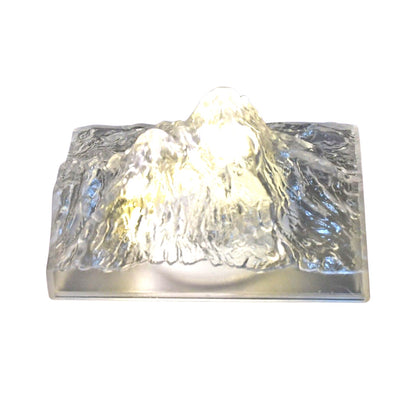A clear, textured iceberg-shaped LED light glows warmly against a plain white background.