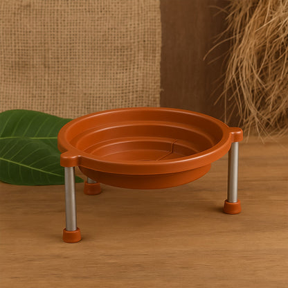 Orange plastic stand with three silver legs on a wooden surface, with a burlap background and green leaf.