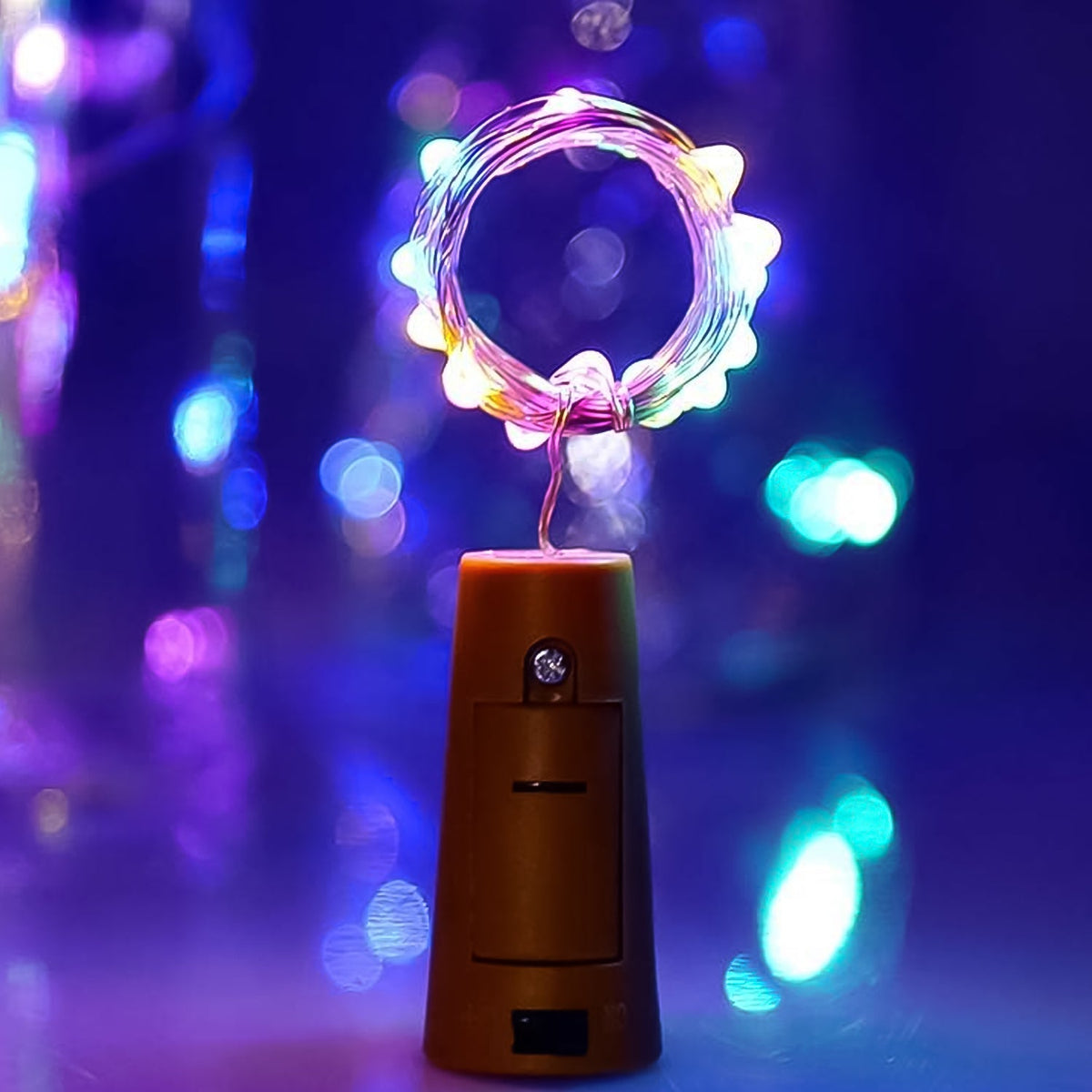 A single bottle cork light with a coiled string of multi-color LEDs glowing brightly against a blurred purple background.