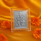 Silver-plated Ganesha idol in a clear acrylic frame, surrounded by orange marigold flowers on a golden silk background.
