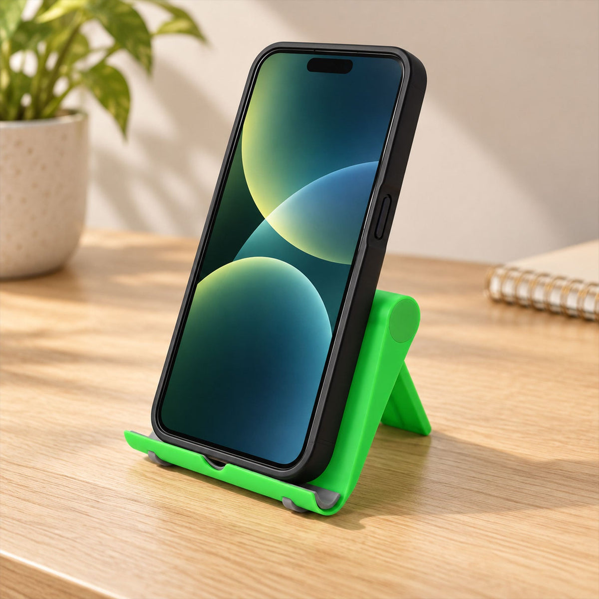 A black phone stands upright on a vibrant green holder, positioned on a light brown wooden surface.