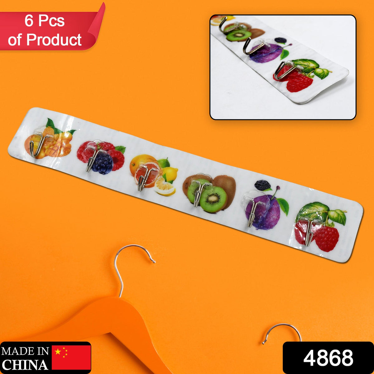 A white adhesive wall hook strip with fruit designs is displayed against a vibrant orange background with a hanger.