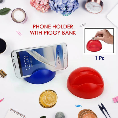 A blue phone holder with a phone and a red piggy bank with coins on a white desk with various office items.