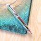 A clear 6-in-1 multicolor ballpoint pen with red, black, green, and blue ink cartridges rests on a teal and brown surface.