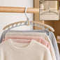 A beige and white folding hanger holding a cream sweater and light colored pants on a wooden rail. Inset shows the hanger