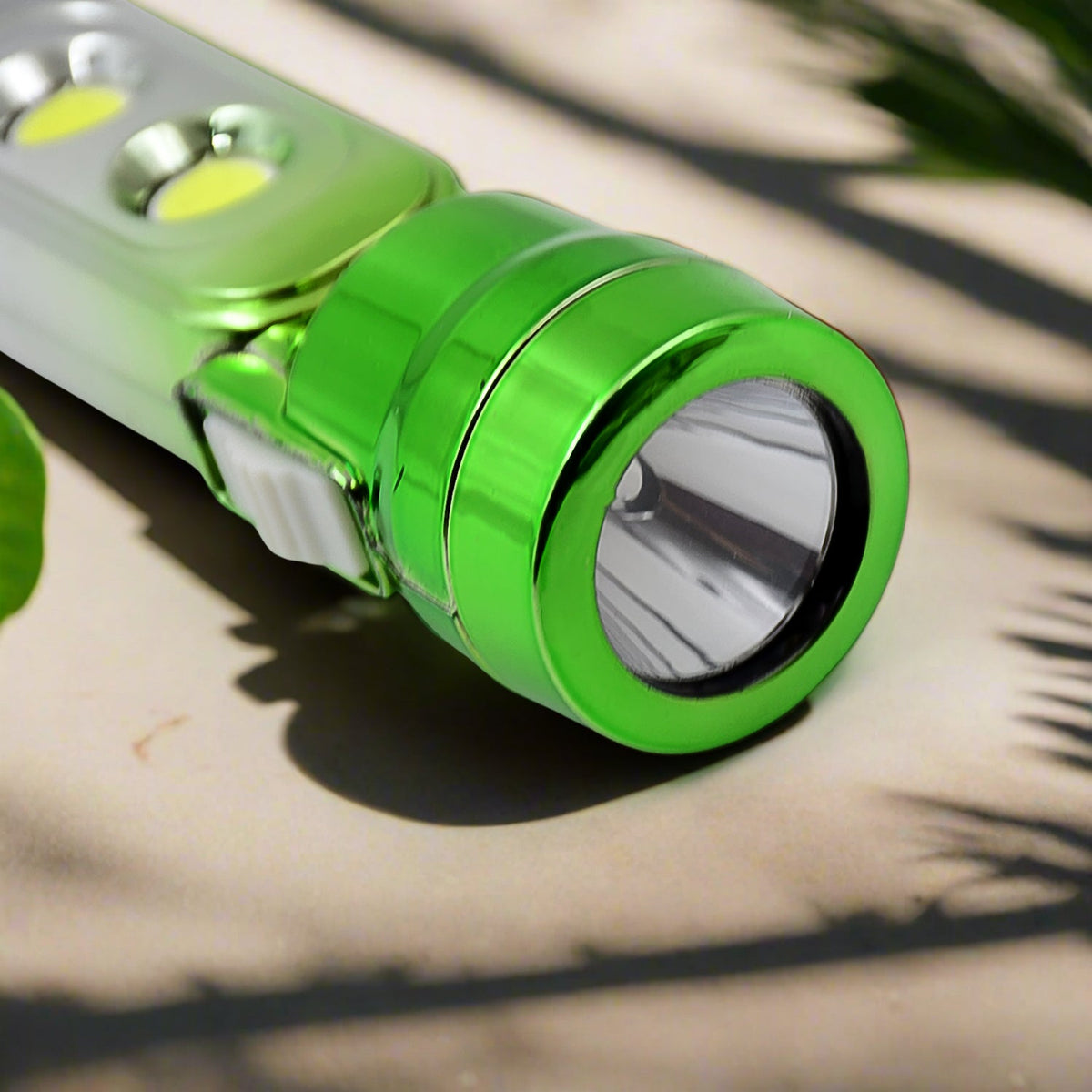 A close-up of the green end of the torchlight, highlighting the main light and the white power switch, with plant shadows.