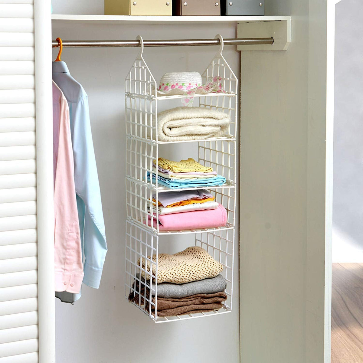White 5-layer plastic hanging closet organizer with folded clothes and a hat in a white closet.