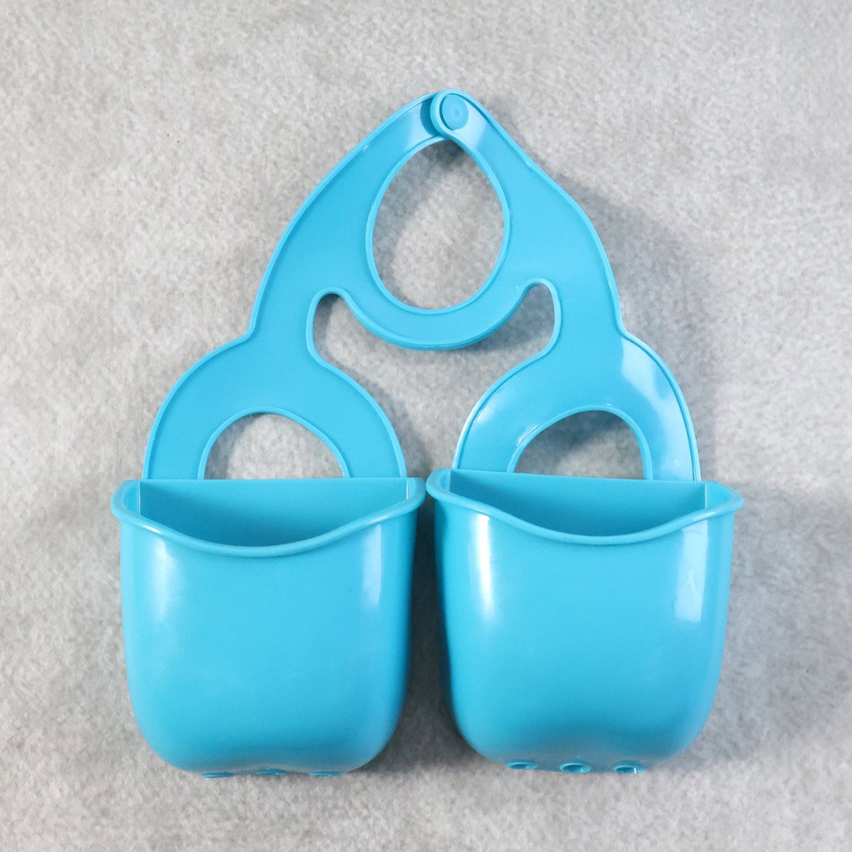 Front view of the blue plastic sink caddy with two compartments on a textured gray background.