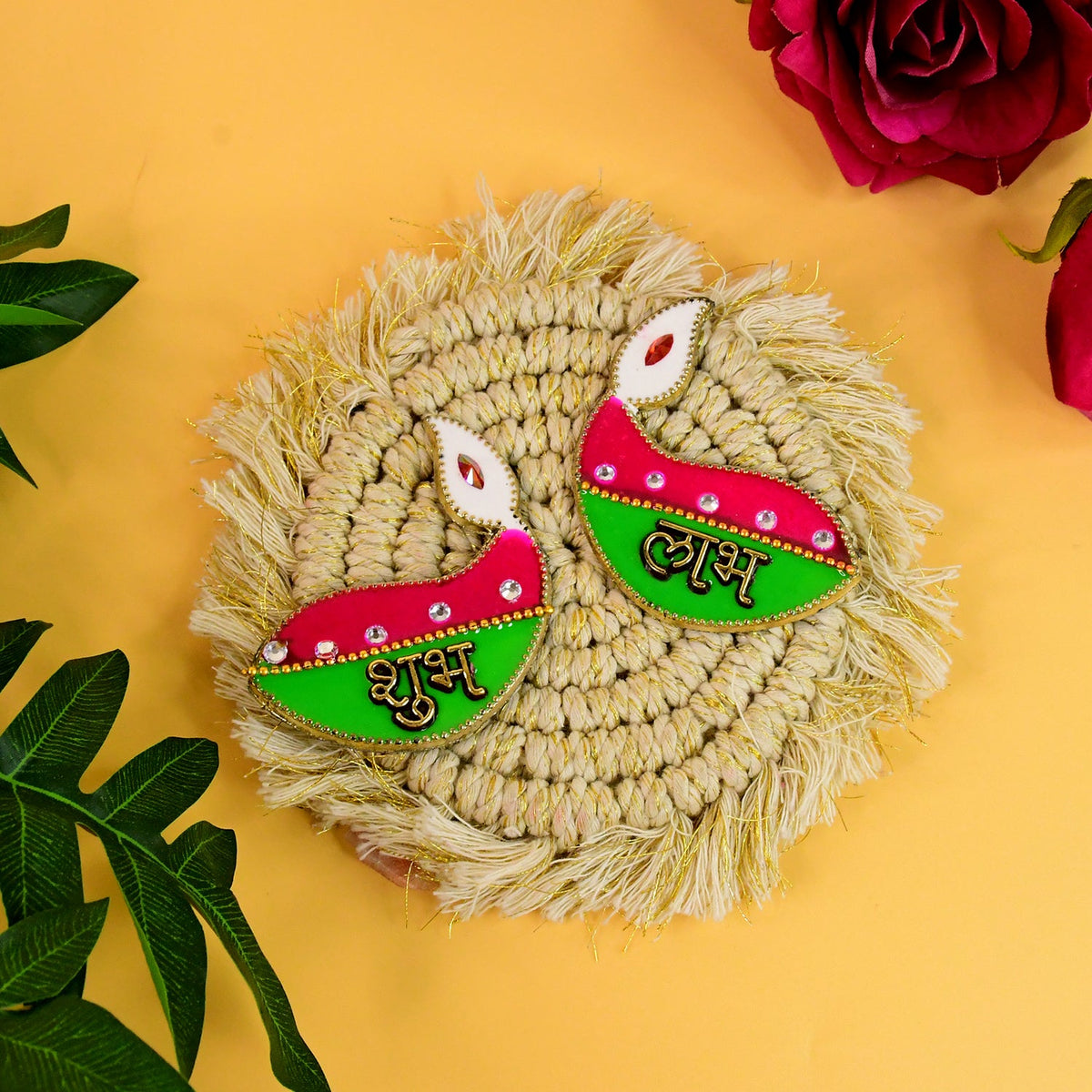 Two pink and green diya-shaped stickers with 'Shubh' and 'Labh' on a round, woven, fringed beige mat.