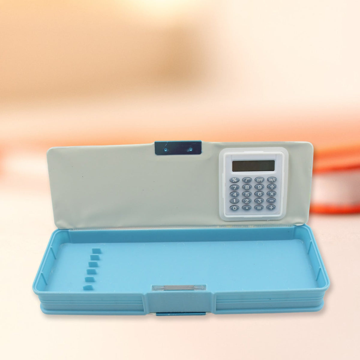 An open blue pencil case reveals a light gray interior lid with a calculator and a blue bottom compartment with dividers.