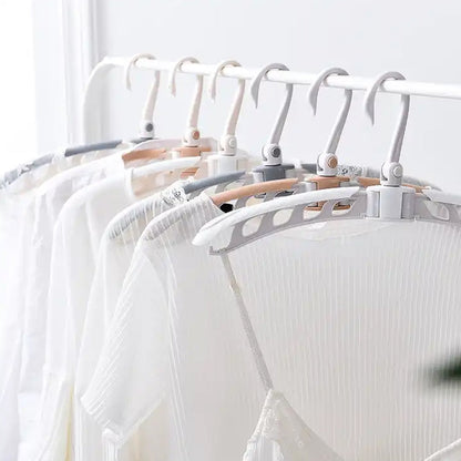 A row of white, beige, and gray folding hangers holding white shirts on a white clothing rack.