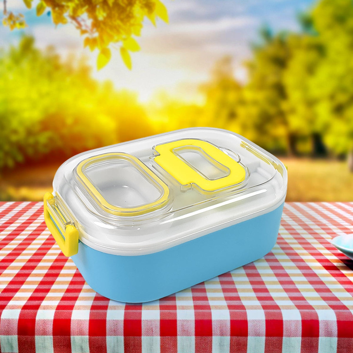 A blue and white lunch box with yellow clasps sits on a red and white checkered tablecloth outdoors.