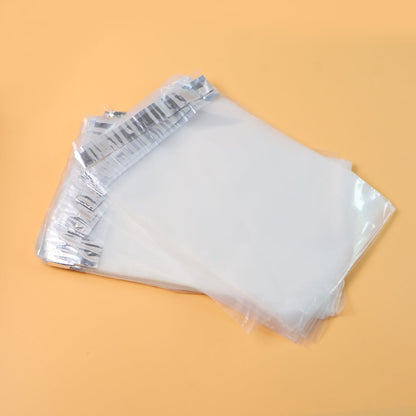 A stack of clear polybags with silver adhesive strips, angled on a light orange background.