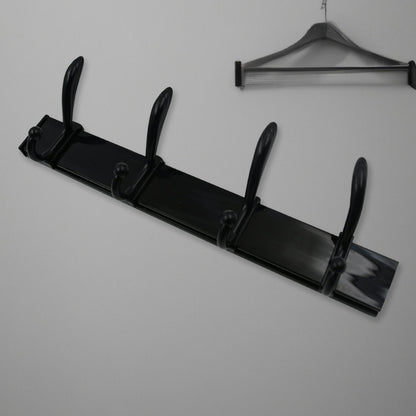 Black four-hook coat rack mounted on a light wall, with a dark wooden clothes hanger visible above it.