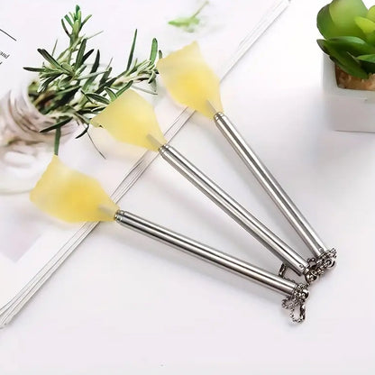 Three silver telescoping back scratchers with yellow hand-shaped heads lying on a white surface with a plant in the