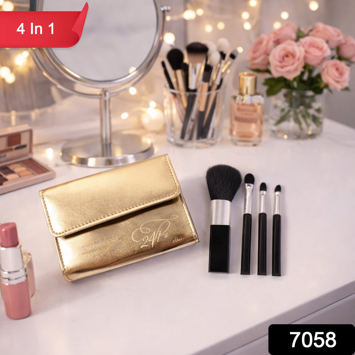 A gold makeup brush pouch and four black brushes on a white table with a mirror and flowers in the background.