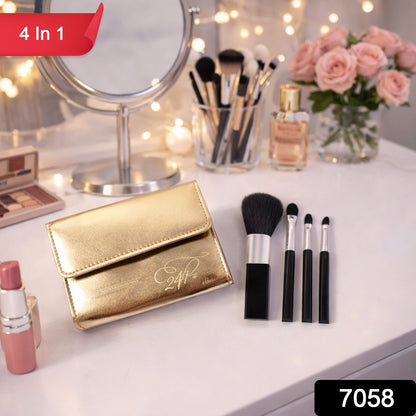 A gold makeup brush pouch and four black brushes on a white table with a mirror and flowers in the background.