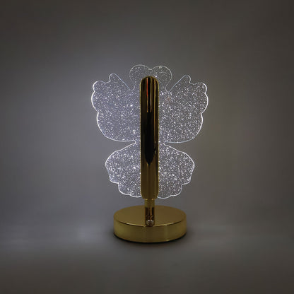A glowing crystal butterfly-shaped table lamp with a gold base and stem, centered on a plain gray background.
