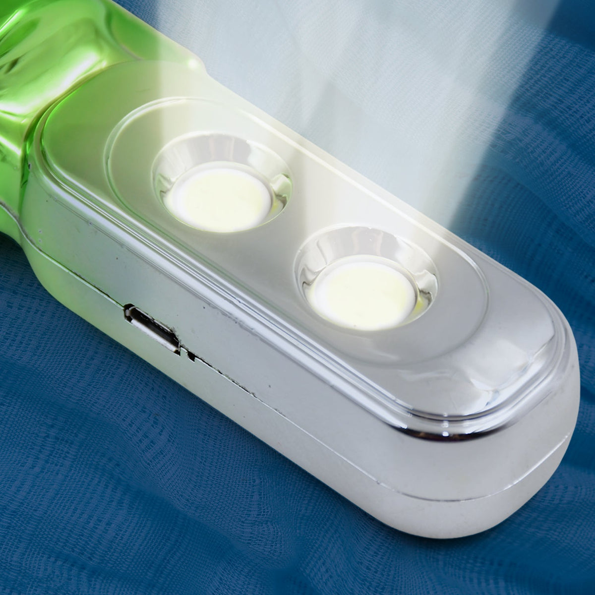 A close-up of the silver section of the torchlight, showing two bright LED lights and a small charging port.