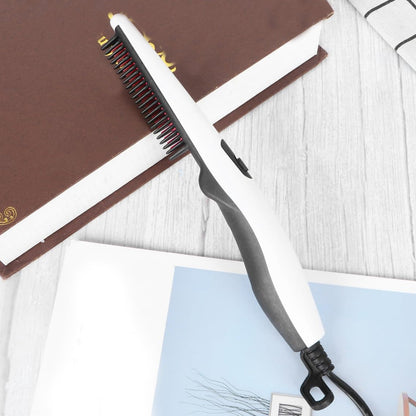 A white and black electric hair and beard straightening comb rests on an open book and a patterned sheet.