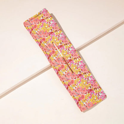 Pink and yellow floral hair bun maker with a metal wire visible through the central opening.