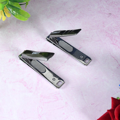 Two black and silver nail clippers, partially open, on a pink marble surface with a red flower in the corner.