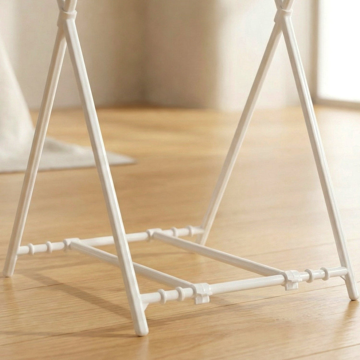 Close-up view of the white plastic base and connecting pieces of the bag holder on wood flooring.