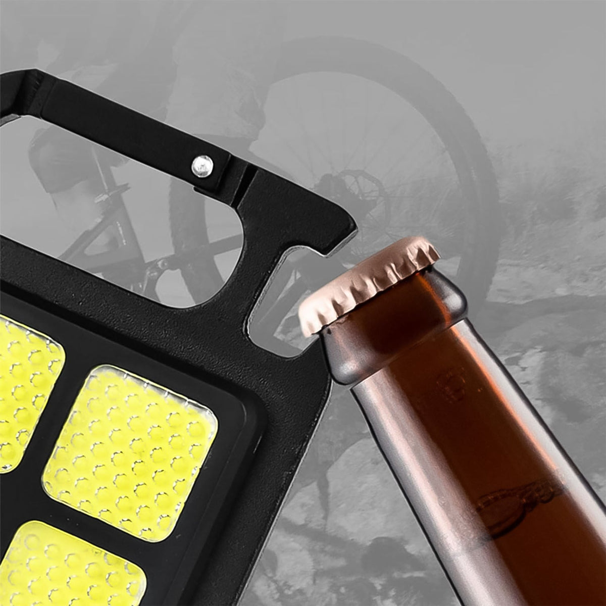 A close-up of the black LED keychain light's bottle opener feature being used to open a brown glass bottle.