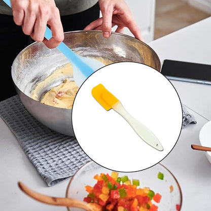 A hand uses a blue spatula to mix dough in a metal bowl, with a yellow spatula highlighted in a circular inset.