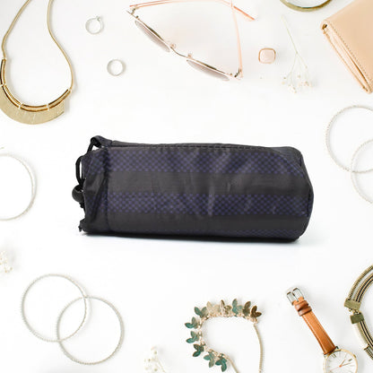 A navy blue drawstring pouch with vertical stripes lies flat on a white surface, surrounded by various pieces of jewelry and