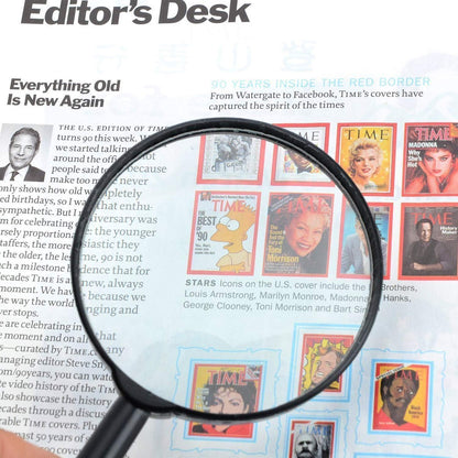 A black magnifying glass magnifies a section of a magazine page featuring various celebrity covers.