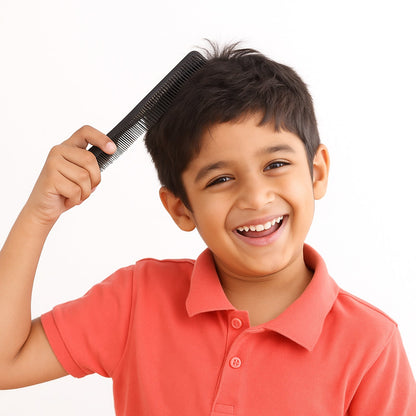 A smiling young boy in a coral shirt combs his dark hair with a black comb.