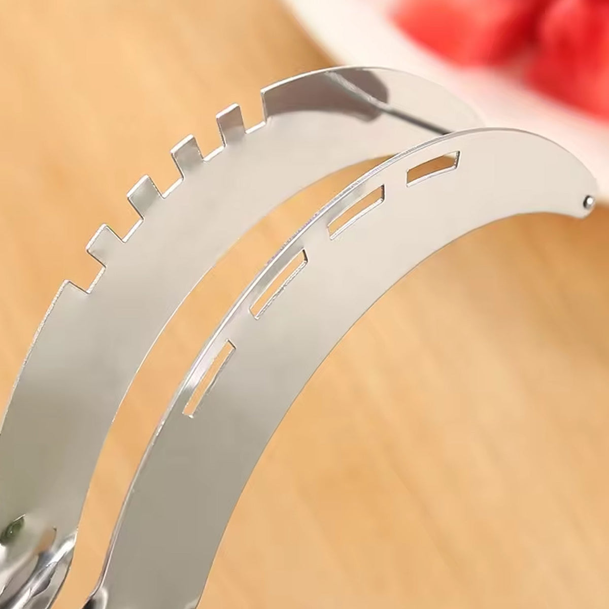 A close-up view of the serrated and slotted edges of a stainless steel watermelon slicer.