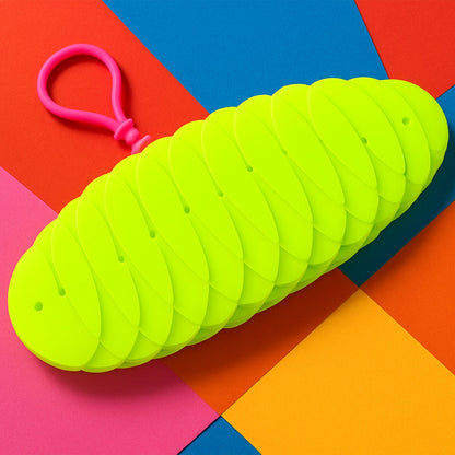 A bright green collapsible silicone ball keychain with a pink loop, shown partially collapsed on a vibrant multi-colored