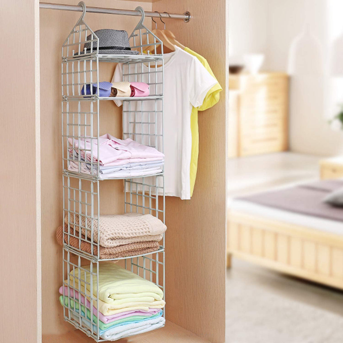 Grey 5-layer plastic hanging closet organizer filled with folded clothes and hats in a closet.
