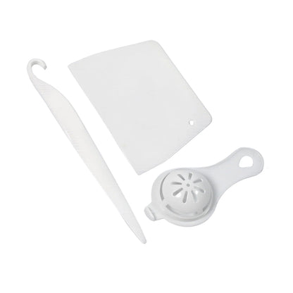 Three white plastic baking tools, including a scraper, a curved tool, and an egg separator, are arranged on a white