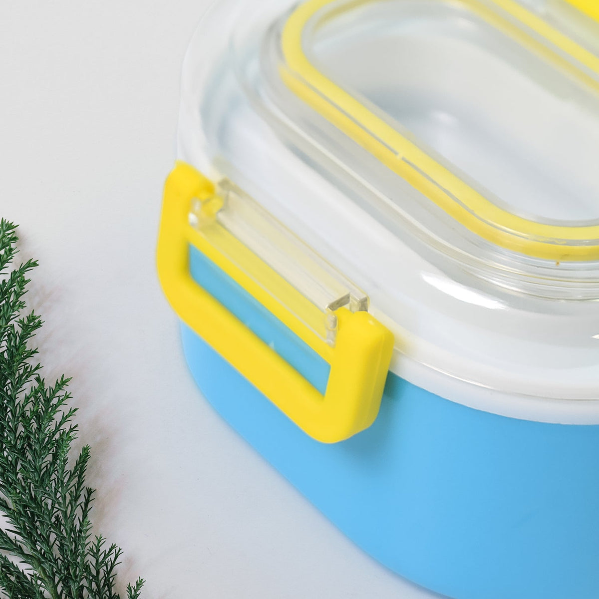 A close-up view of the yellow clasp on the side of the blue and white lunch box.
