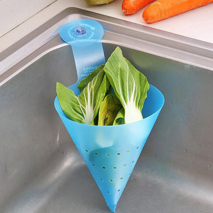A blue silicone sink strainer with a suction cup, holding green leafy vegetables, attached to a metal sink.