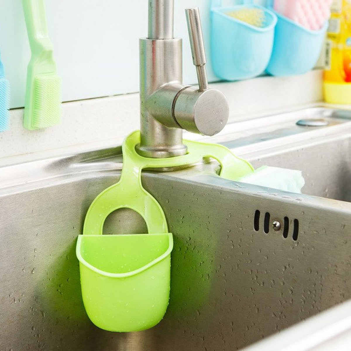 Green plastic sink caddy hanging from a kitchen faucet, with other caddies in the background.