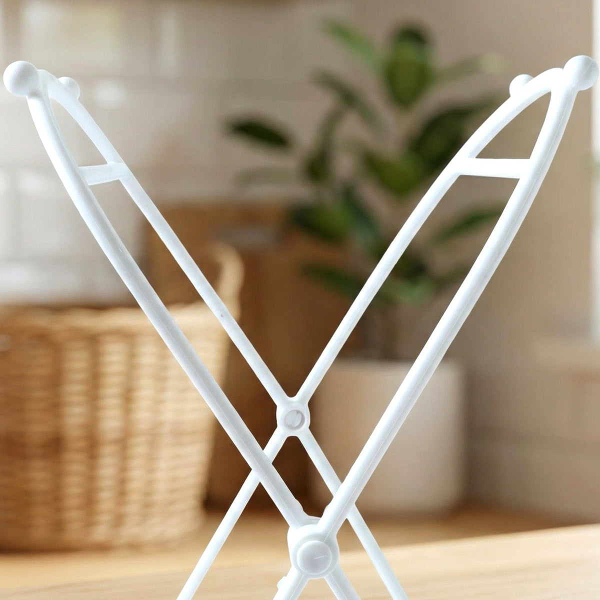 Close-up of the top portion of the white plastic bag holder, with a plant in the background.