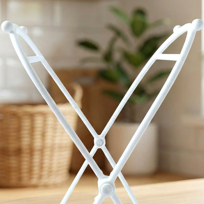 Close-up of the top portion of the white plastic bag holder, with a plant in the background.