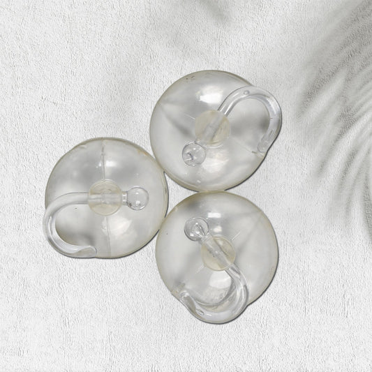 Three transparent suction cup hooks are arranged on a white textured surface with a subtle shadow.