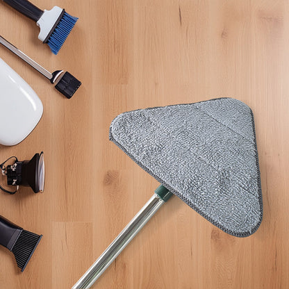The gray microfiber head of the green triangle mop is shown on a light wood floor, surrounded by various cleaning tools.