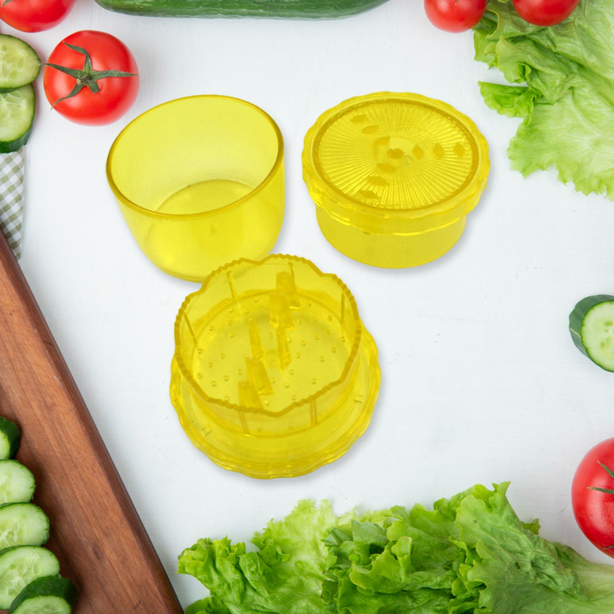 The yellow plastic manual food grinder is disassembled, showing its three components on a white surface with fresh